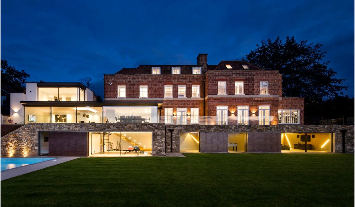 a modern renovation of a brick building in totteridge with a large glazed extension shown at dusk