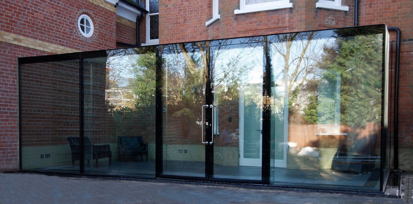 a flush glass conservatory attached to a red brick house