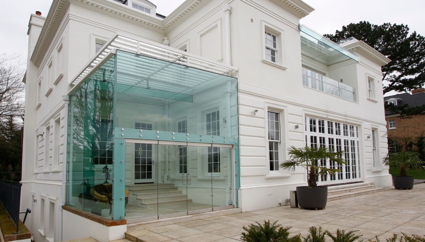 a double height conservatory attached to a white neoclassical house