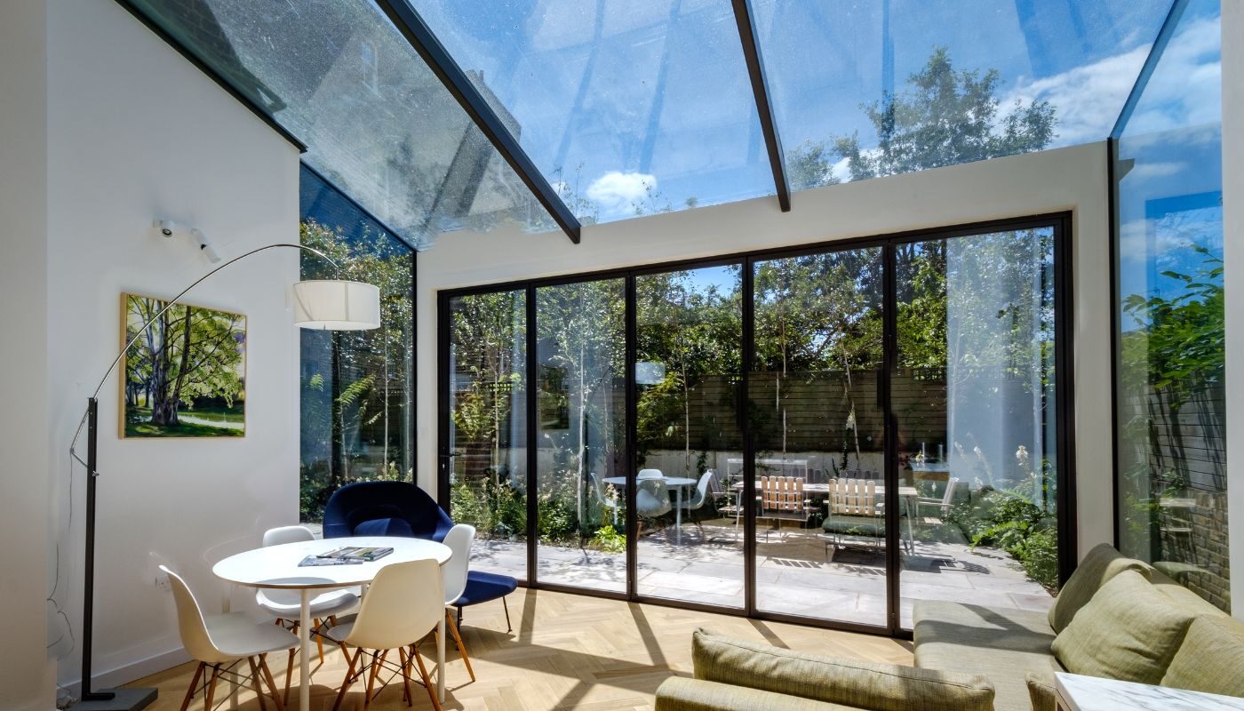 a glass extension with bifold doors shown from the inside with the bifold doors closed overlooking a small garden