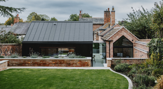 garden view of a modern extension to a traditional red brick gable end building with a glass link between