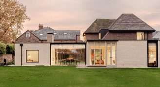 slim sliding glass doors and modern glazing to a house renovation and extension to a traditional cottage in york shown at dusk, viewing the house from the outside