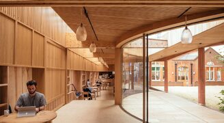 Lea Bridge Library timber and curved glazing with wide apertures in the frameless glass facade