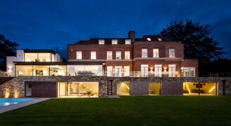 a modern renovation of a brick building in totteridge with a large glazed extension shown at dusk