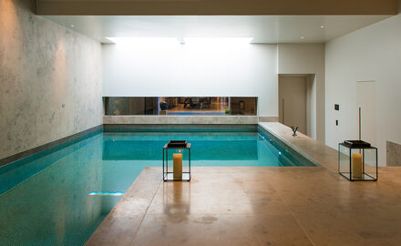 Luxury indoor wellness pool with minimalist architectural glazing and flush glass viewing window, showcasing glazing for specialist wellness spaces.