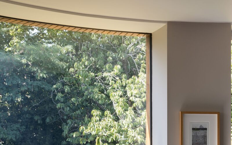 an internal view of a frameless curved window, showing a close up view of the frameless glass interface with the internal plaster