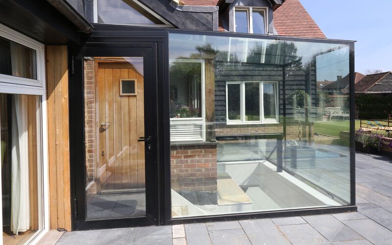 a glass box over an entrance to a basement stairwell attached to a traditional cottage