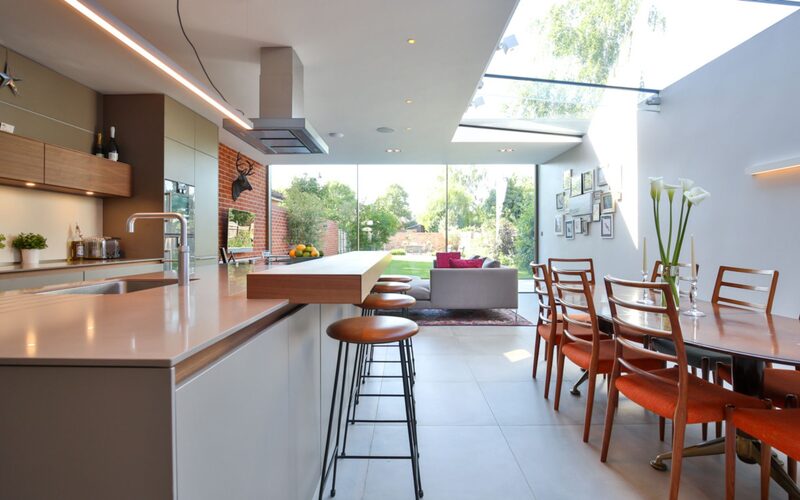a glass kitchen extension with sliding glass doors and a glass strip roof