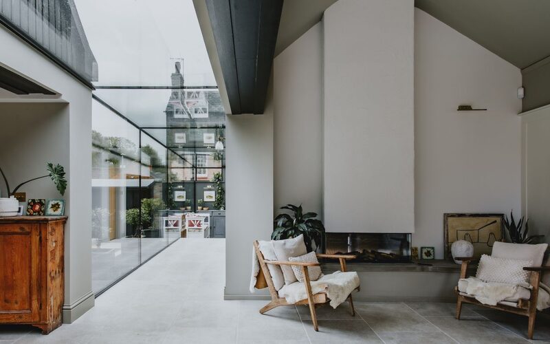 a view down a frameless glass link with a modern fire place on the right