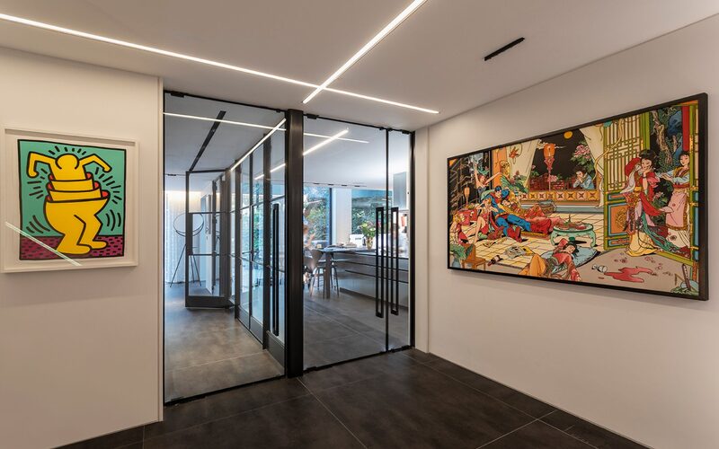 a hallway with fire rated glass doors looking into the kitchen with artwork on the walls