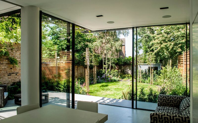 open corner sliding doors shown open looking out over a small back garden of a house extension