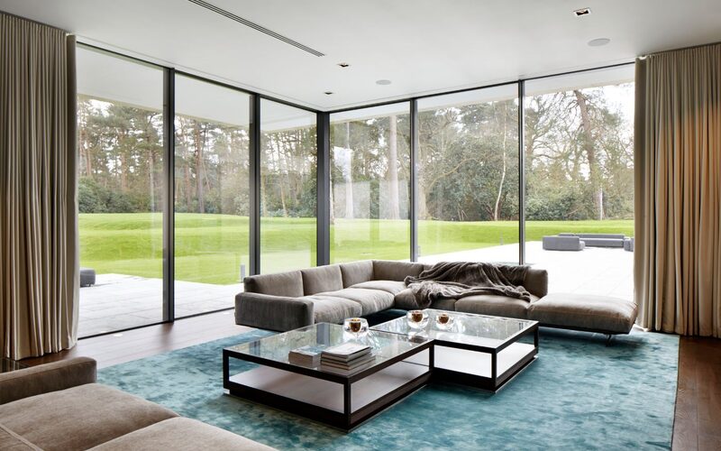 corner sliding doors to a luxury living room with floor to ceiling curtains, looking over the garden