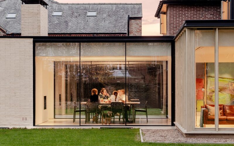 slim sliding glass doors to a glazed extension in york shown at dusk with the lights on inside viewed from the outside with people inside at the dining table
