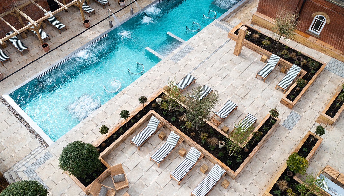 Luxury outdoor spa pool with integrated water jets, landscaped terrace sun loungers and contemporary wellness courtyard design.
