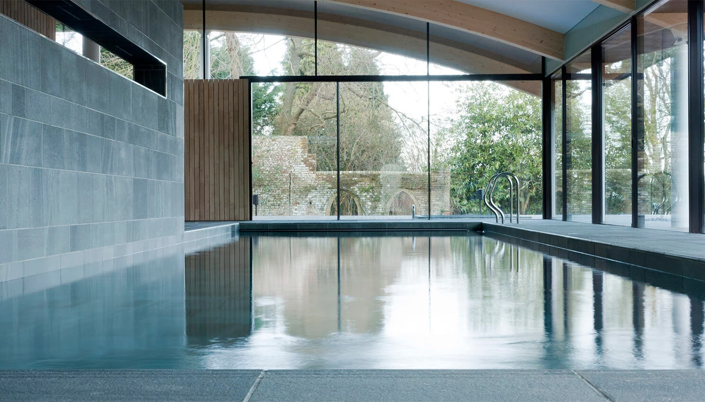Luxury indoor swimming pool demonstrating glazing for specialist wellness spaces, with full‑height structural glass glazing.