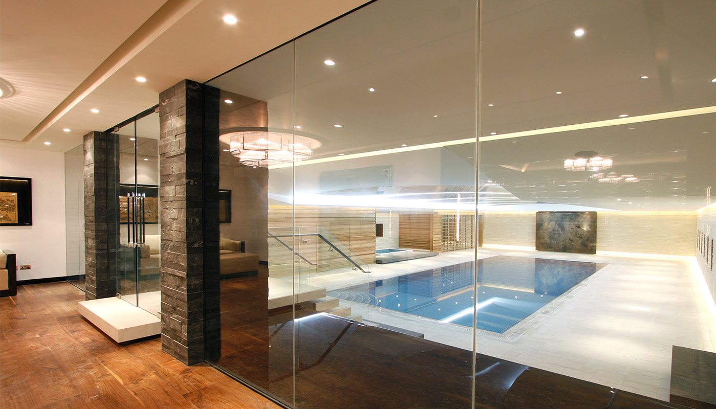 Luxury indoor swimming pool enclosed by frameless glass glazing system.