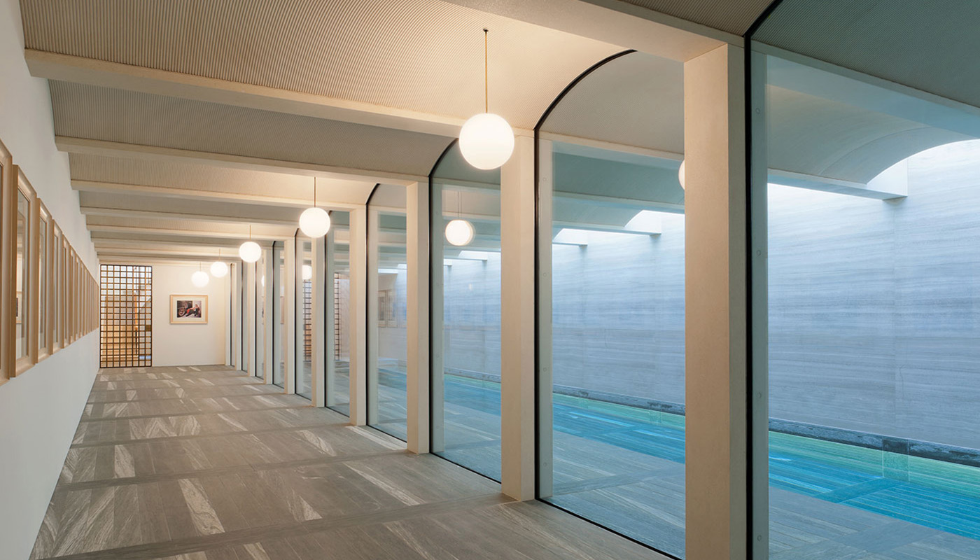 Luxury indoor spa corridor demonstrating glazing for specialist wellness spaces, with frameless floor‑to‑ceiling glass overlooking a swimming pool.