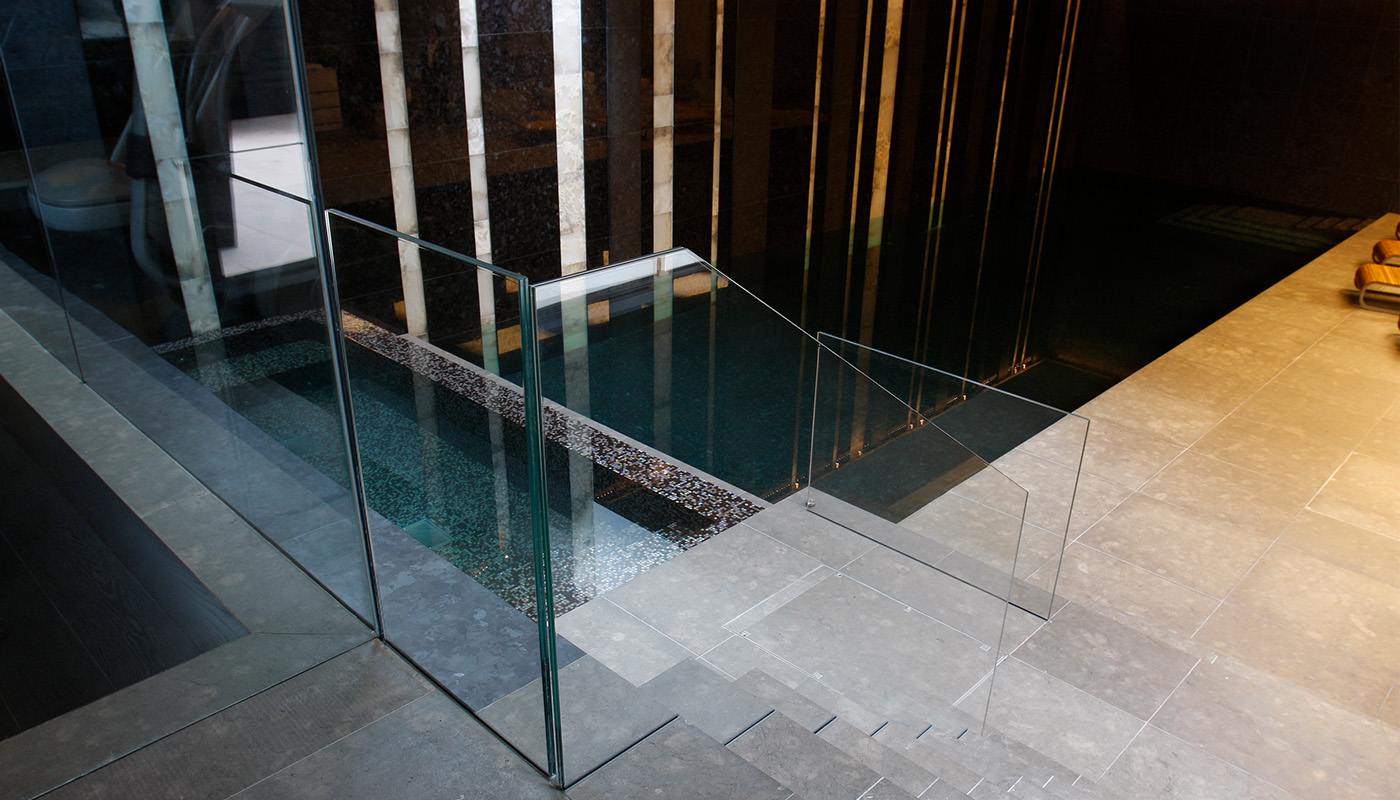 Luxury indoor spa with frameless glass balustrade surrounding a sunken plunge pool, showcasing glazing for specialist wellness spaces.